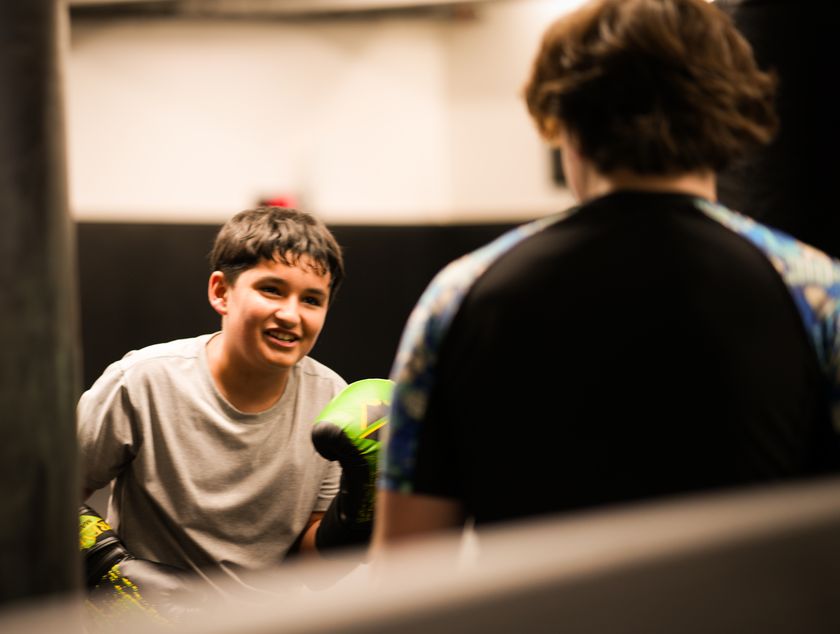 A smiling kid in boxing gloves during a kids Muay Thai class.